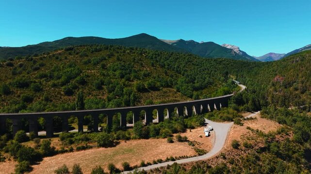 Scenic aerial view of a train crossing an old viaduct in the pyrenees mountains