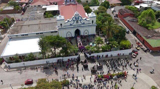 Church in Central America with people celebrating Easter.
Aerial drone footage of Parroquia Inmaculada Concepci&oacute;n de Ataco; Semana Santa Easter procession in Concepci&oacute;n de Ataco, El Salvador.