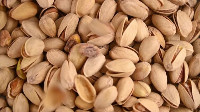 Pistachio nuts pouring and tumbling into pile on tabletop
