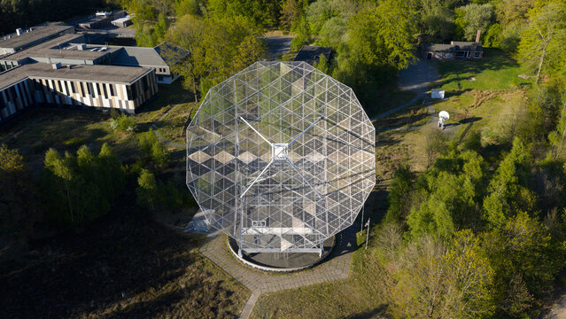 Aerial view of the Radiotelescoop dish structure surrounded by lush green forest and research buildings in Dwingeloo, Drenthe, Netherlands.