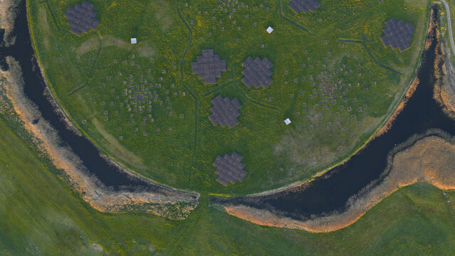 Aerial view of the LOFAR superterp radio telescope antenna arrays on a circular green field surrounded by water channels in Buinen, Drenthe, Netherlands.