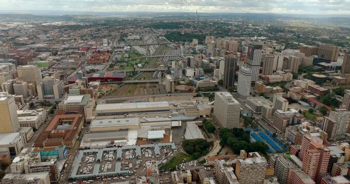 Aerial wide panorama of the Johannesburg city skyline. 4K establishing drone shot of the South African metropolitan horizon, showcasing dense urban architecture and sprawling city landscape