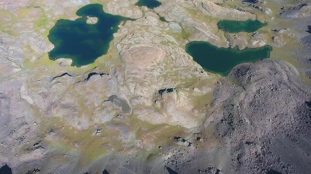 Aerial glacial lakes among barren mountains in eastern Turkey, remote summer highland water. Treeless ridges, clear basins, rugged plateau, open terrain, isolated alpine landscape, stock search.