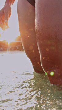 Vertical video. Low Angle View Of Woman In Sea As Wave Covers Body In Slow Motion With Sunlight And Splashing Water, Dynamic Summer Beach Scene