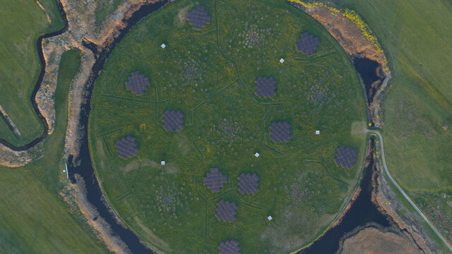Aerial view of the LOFAR superterp radio telescope array with its circular green field and antenna clusters surrounded by a water channel in Buinen, Drenthe, Netherlands.