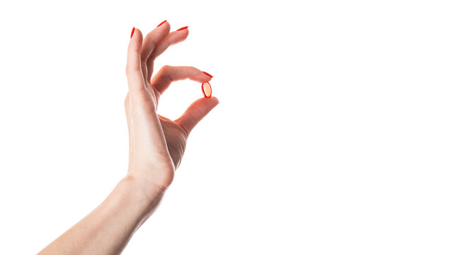 Hand holding a red capsule isolated on white background. Red pill isolated.