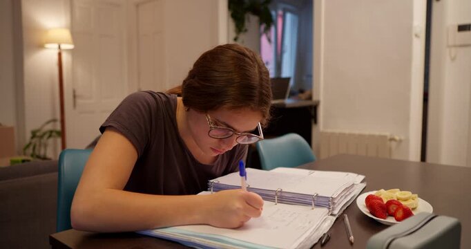 Homework Time: A focused individual sits at a table, engrossed in studying, surrounded by textbooks and the tools of learning. A lamp casts a warm glow, setting a studious scene of diligent efforts.