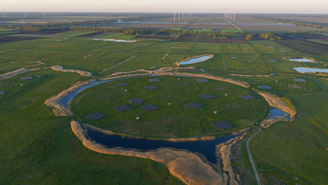 Aerial view of the LOFAR superterp radio telescope station featuring a circular island with antenna arrays surrounded by water and green fields in Buinen, Drenthe, Netherlands.