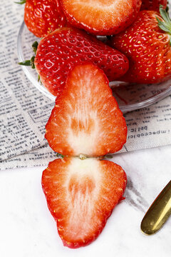 Fresh Dandong Strawberries Cut in Half Showing Interior on Newspaper Background Studio Shot
