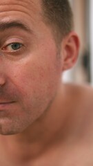 Naklejka premium Vertical photo Closeup facial portrait, Intimate male skin examination, Focus on facial features, skin texture, Closeup view capturing male facial details with emphasis on skin, emotional expression
