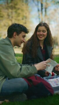 High school friends are happily studying a human heart model in a park. They are enjoying an educational outdoor activity together.