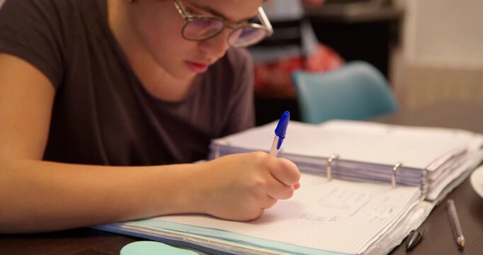 Focused Study: A young individual, immersed in a world of learning, diligently writes in a notebook, her face etched with concentration and focus.