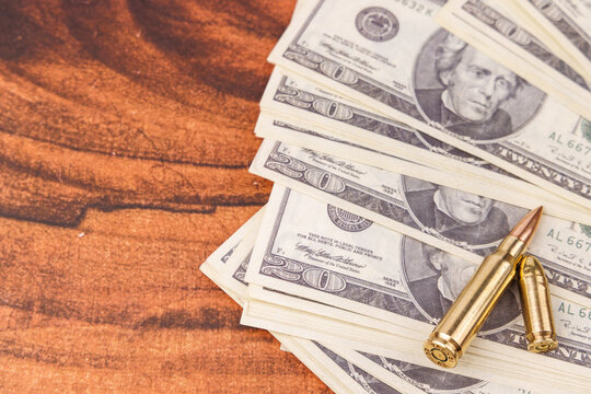 Twenty dollar banknotes and bullets on a mahogany table representing the dark intersection of wealth and lethal violence nowadays.