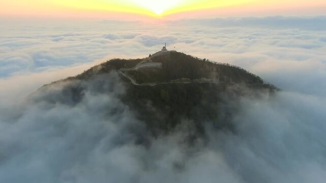Aerial mosque and minaret above cloud ocean at sunrise during Ramadan, serene prayer scene. Islamic shrine, misty ridge, dawn glow, spiritual worship, tranquil Sufi sanctuary, stock search wording.