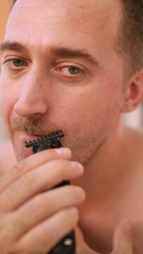 Vertical photo Man grooming routine, Detailed image of man tidying mustache, Gentle grooming session with soft bathroom lighting focus, Careful man smoothing, shaping facial hair in soothing bathroom