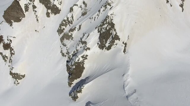 Aerial winter panorama shows snowy Alps mountain ridges and glaciers across vast peaks. Cinematic high altitude scenery reveals pristine white summits, icy slopes, remote European wilderness.