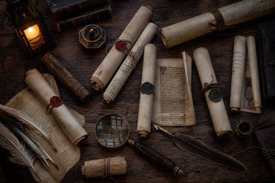 Ancient scrolls and quill pens on dark wooden table