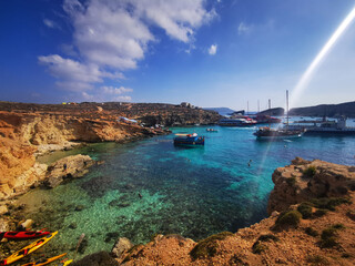 Turquoise bay of Malta with boats anchored in clear shallow water. The image conveys the concept of coastal nature and Mediterranean summer seascape. © Natallia