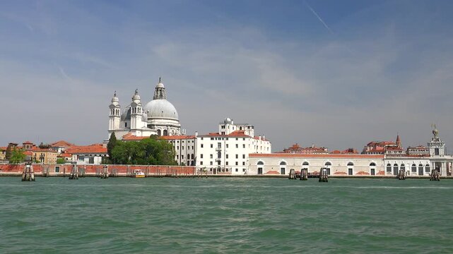 Venice waterfront church, cathedral skyline with bell tower across lagoon in Italy. Historic Christian basilica, campanile rise beside Adriatic waters, iconic Venetian landmarks.