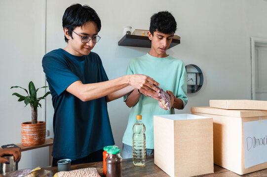 Young volunteers organizing food donation parcels for charity