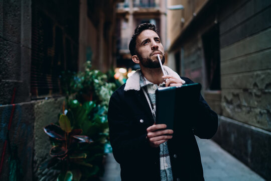 Cheerful man looking up with joy holding digital tablet, happy handsome guy celebrating success or good news, winning opportunity and digital nomad lifestyle concept, urban background.