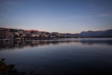 Obraz premium Panorama of Lugano luxury houses and hotels in autumn early morning with Swiss and Italian mountains in the background. Lugano, Ticino, Switzerland