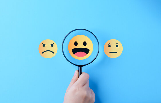 Customer satisfaction survey and positive feedback concept. hand holding magnifying glass over happy emoji, showing service quality, user experience, opinion research, review choice, and mental health