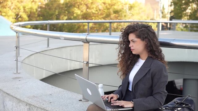 A professional woman is working outdoors with her laptop, embodying modern business ideals