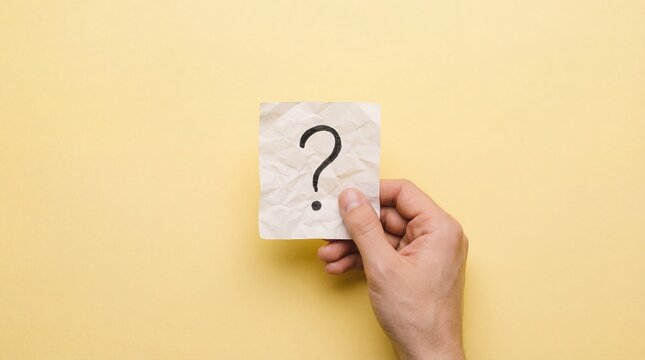 caucasian hand holding crumpled paper with black question mark against yellow background. concept of uncertainty, faq, problem solving. banner, website header, copyspace.