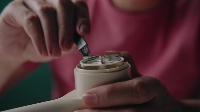 Person hands cleaning blades of modern electric lint remover with specialized small brush, performing routine maintenance on household appliance for clothing care, close-up. Shooting in slow motion.