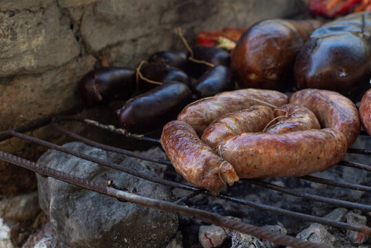 Traditional Argentine preparation of chorizo ​​and morcilla grilled over a rustic wood fire outdoors.