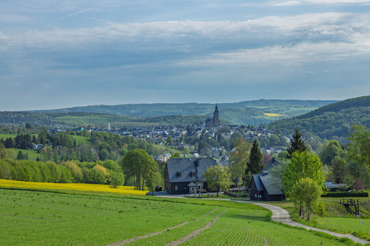 Malerische s&auml;chsische Mittelgebirgslandschaft mit bl&uuml;henden Rapsfeldern und Blick auf die Bergstadt Schneeberg im Erzgebirge