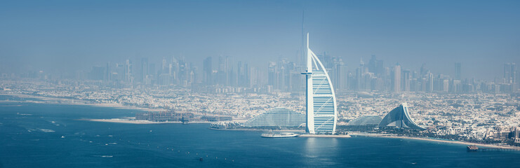 Obraz premium 14 January 2026, Dubai, UAE: Burj Al Arab hotel standing prominently along the Jumeirah coastline with skyline and the Persian Gulf on a clear day