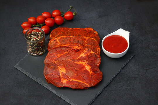 Marinierte Schweinenackensteaks auf Schieferplatte mit Gew&uuml;rzen, Tomaten und Ketchup