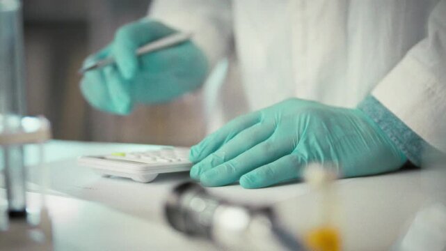 In a bustling laboratory, a scientist carefully operates a calculator to compute experimental data, exemplifying the meticulous work of a laboratory worker dedicated to precise analysis
