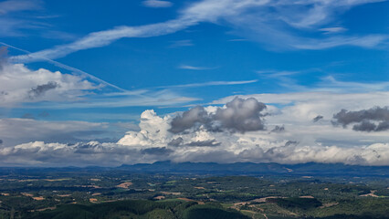 A wide-angle composition that highlights the contrast between a dynamic, cloud-laden sky and the vast, varied vegetation at its base. © Roberto
