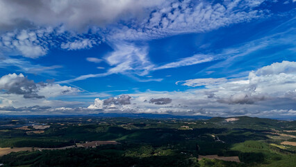 A wide-angle composition that highlights the contrast between a dynamic, cloud-laden sky and the vast, varied vegetation at its base. © Roberto