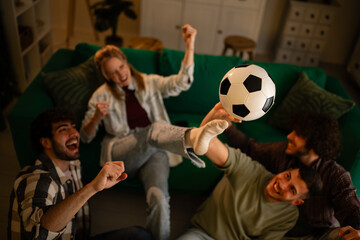 Fototapeta premium Friends cheering watching football match at home