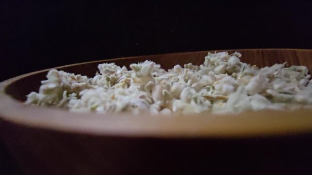 Macro shot of dried Teucrium polium (Felty Germander), a medicinal mountain herb from the Saudi desert used in folk medicine and blood sugar regulation, served in a wooden bowl.