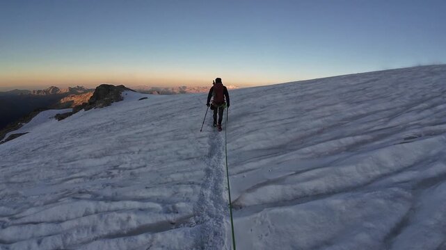 POV mountaineering in rope team with mountaineers and mountain glacier panorama with summit Gran Paradiso in the background in the morning in Pennine Alps, Italy
