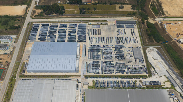 Aerial view of the BYD Thailand Rayong Office Building and extensive parking areas filled with rows of new cars in Phananikhom, Rayong, Thailand.
