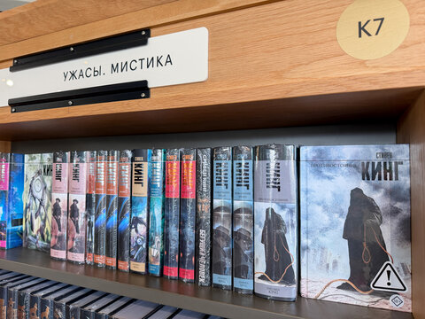 Saint Petersburg, Russia - April 27, 2026: A collection of horror and mystery novels by Stephen King arranged on a wooden shelf in a library section marked K7