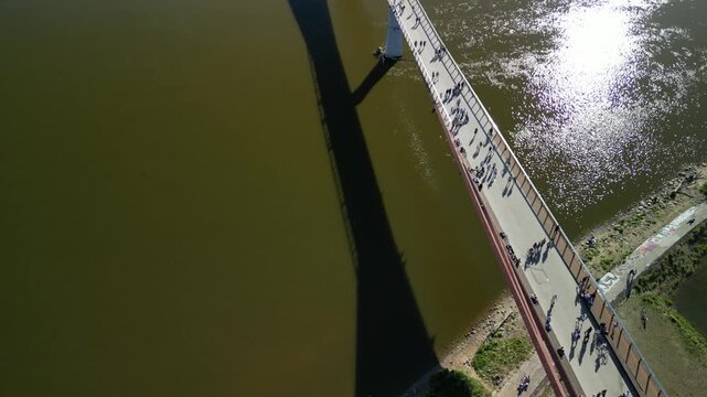 Warszawa - Polska - panorama miasta i kładka pieszo rowerowana na rzece Wisła nagrane dronem. Słońce, panorama miasta, drapacze chmur, krajobraz miasta z drona