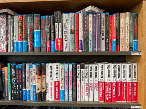 Saint Petersburg, Russia - April 27, 2026: A vibrant assortment of books arranged on a wooden shelf, showcasing various genres and titles in different colors and sizes