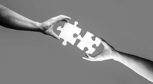 Jigsaw puzzle. Business solutions, success and strategy concept. Two hands trying to connect couple puzzle piece. Black and white