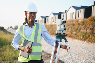 African american surveyor working with theodolite on construction site