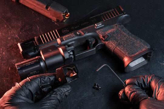 BALTIC STATES &mdash; May 4, 2026: A gunsmith installs a red dot sight on a Glock 19 Gen 5 pistol using professional tools in a workshop.
