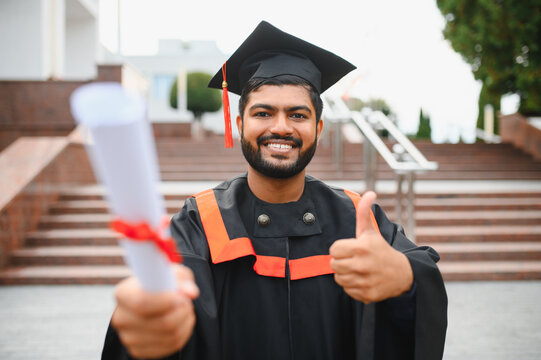 Indian university graduate holding diploma, showing thumbs up