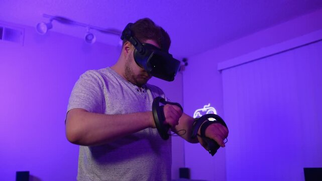Man adjusting virtual reality controllers before starting game at home preparing equipment and interacting with modern technology in room with neon lighting
