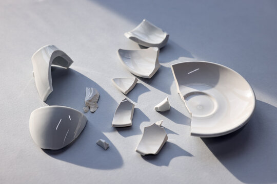 Pieces of broken saucer and cup on light grey background, closeup